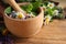 Mortar and different healing herbs on table, closeup