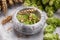 Mortar, fresh hops and ears of wheat on light grey marble table, closeup