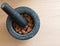 A mortar full of almonds with a pestle on top on a wooden table