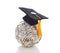 A mortarboard on a ball of one hundred dollar bills representing the high cost of a college education