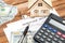 Mortgage deed with calculator, money, model of house and key on the wooden background. Real estate concept