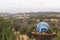 Mosaic garden ball in multicolored shades of blue made from stained glass tiles, hills and mountains landscape in background