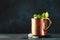 Moscow mule cocktail in copper mug with lime, ginger beer, vodka and mint. Blue table, copper bar tools, copy space