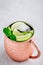 Moscow mule ice cold cocktail in copper cup with lime and and mint on gray stone background