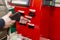 Moscow, Russia, 04/29/2020: A red service-service cashout kiosk at a supermarket with a hand and a smartphone. Background in focus