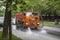 Moscow/ Russia - 15.06.2019: Modern orange truck water road cleaner on the street of a modern city among green trees and a lawn