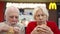 MOSCOW, RUSSIA- CIRCA JANUARY 2018: Hungry seniors eating hamburger at McDonald`s on food court