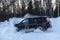 Moscow, Russia - February 15, 2021: Kia Mohave 2021 black SUV stands on the road in winter forest, snowdrifts. Side view