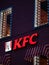 Moscow, Russia - January 17, 2020: KFC logo with red lights on wall of house in evening. Luminous windows with visors made of