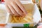 Moscow, Russia - July 26, 2019: A teenager hand taking a piece of french fries out of a paper disposable takeaway box in