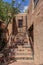 Mosiac steps leading up to second story entrance and a locked iron gate in an adobe building