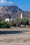 A Mosque and clocktower hidden in the trees against a beautiful rocky mountain and blue sky background on the coast of Oman near t