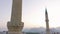 Mosque with two minarets against sunset sky. Silhouettes of mountains in the background.