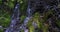 Moss covered rocks make up a waterfall on the side of a hiking trail to the summit of Mount Timpanogos