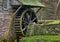 Moss covered water wheel and stone retaining wall of a historic