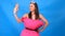 The most beautiful girl in a pink dress from pillows makes a selfie on a blue background. Crazy quarantine. Fashion 2020