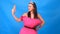 The most beautiful girl in a pink dress from pillows makes a selfie on a blue background. Crazy quarantine. Fashion 2020