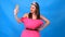 The most beautiful girl in a pink dress from pillows makes a selfie on a blue background. Crazy quarantine. Fashion 2020