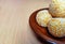 The most delicious onde-onde cake, a typical Indonesian food. On a small brown plate. Isolated on a wooden patterned background.