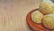 The most delicious onde-onde cake, a typical Indonesian food. On a small brown plate. Isolated on a wooden patterned background.