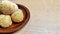 The most delicious onde-onde cake, a typical Indonesian food. On a small brown plate. Isolated on a wooden patterned background.