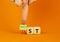 Most or least symbol. Businessman turns wooden cubes and changes the word Least to Most. Beautiful orange table orange background