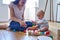 Mother With 8 Month Old Baby Son Learning Through Playing With Coloured Wooden Blocks At Home