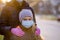 Mother adjusts her daughter`s medical mask on the street of a European city . The concept of protection against coronavirus