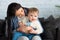 mother with adorable baby boy on hands sitting on sofa