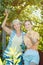 Mother and adult daughter checking apples in tree