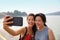 Mother adult daughter traveling together in Asian taking selfie picture with mobile phone. Smiling Asian family outside