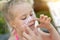 Mother applying sunscreen protection creme on cute little daughter nose face. Mom using sunblocking lotion to protect kid girl