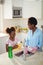 Mother assisting her daughter in cleaning utensils