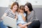 Mother, Aunt and kid having time together lerning with using laptop at home on couch, family concept.