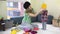 Mother with awesome baby girl measure colorful knitted hats between toys