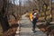 mother with baby in baby carrier walks by the forest winding road