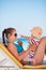 Mother with baby on beach playing with sunglasses