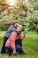 Mother and baby in blooming garden. Mom and child in spring. Springtime family scene. Flowers of apple or cherry tree