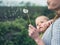 Mother with baby blowing dandelion