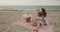 Mother and baby daughter sit on the beach near the sea playing together