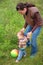 Mother and baby play with ball on grass