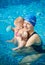 Mother with baby in pool. Smiling woman looking in camera, having fun, swimming time with newborn child playing in water