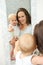 Mother and baby in reflection of mirror in bathroom