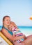 Mother and baby relaxing on sunbed on beach