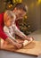 Mother and baby rolling pin dough in christmas decorated kitchen