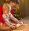 Mother and baby rolling pin dough in christmas decorated kitchen