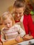 Mother and baby rolling pin dough in christmas decorated kitchen