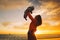 Mother and baby silhouettes at sunset on the sea beach