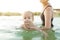 Mother and baby on the water. Mom and little child swimming and playing in water.