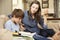 Mother Becoming Frustrated With Son Whilst Doing Homework Sitting On Sofa At Home